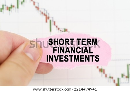 Business and trading concept. Against the background of the quote chart, a man holds a sign with the inscription - Short Term Financial Investments