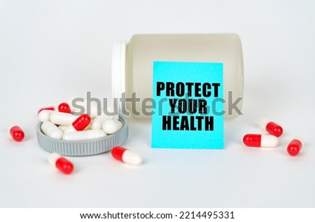 Medical concept. On a gray background, a jar, capsules and a sign with the inscription - PROTECT YOUR HEALTH