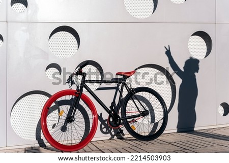 Modern red bicycle parked in the street against white wall with cool design.