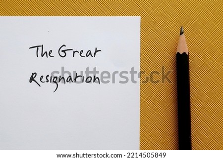 On yellow background, pencil writing on note paper THE GREAT RESIGNATION, the BIG QUIT trend where millions of American employees voluntarily quit their jobs  after pandemic for work life balance Royalty-Free Stock Photo #2214505849
