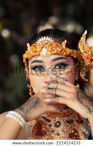 Beautiful Indian bride wearing a golden crown and a golden necklace with tattoos on her hands before the wedding ceremony