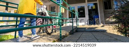 Mother pushing wheelchair with her daughter, young girl living with cerebral palsy, on their way to therapy. Cerebral palsy is lifelong condition that affects movement and co-ordination. Royalty-Free Stock Photo #2214519039