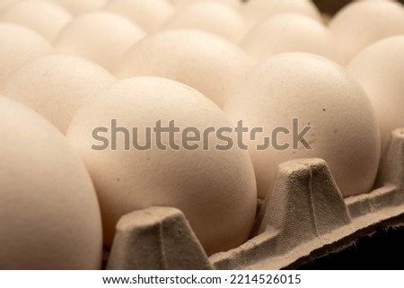 White chicken eggs in a cardboard box on the table. Close-up, selective focus.