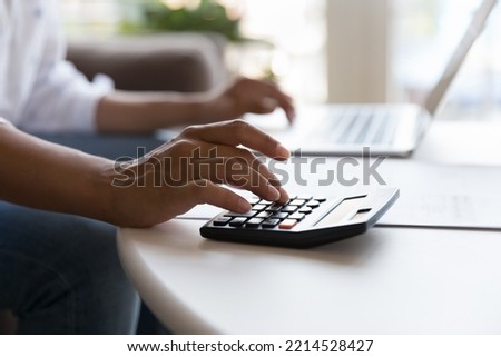 Unrecognizable female hands use calculator and laptop seated at table, close up. Unknown woman paying bills through e-bank application, accountant working, prepare financial report. Savings, finances Royalty-Free Stock Photo #2214528427