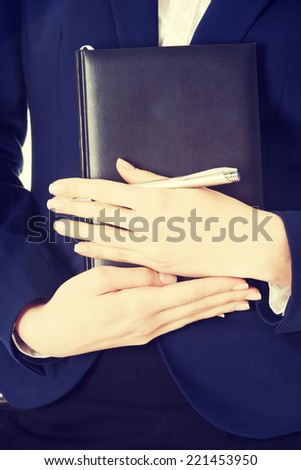 Close uo on notebook and pen in business woman's hands.