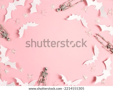 Halloween frame of white paper bats, skeletons and spiders on pastel pink background. Flat lay, top view, copy space.