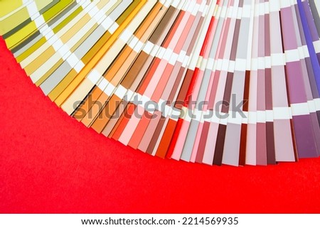 Color guide close up. Assortment of flowers for design. Color palette fan on red background A graphic designer selects colors from a color palette guide. Color swatch catalog