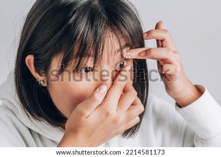 Close-up shot of young asian woman wearing contact lens. vision correction, advertising medical products Royalty-Free Stock Photo #2214581173