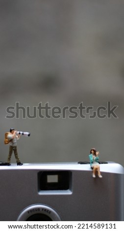 miniature figure of a photographer photographing a model on a film camera.