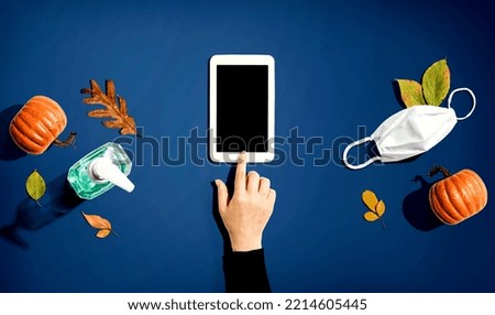 Tablet computer with a mask and a sanitizer bottle in Autumn