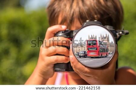 Young girl taking photos of London Bus by professional digital camera.