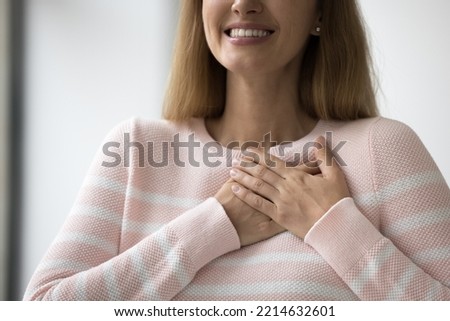 Sincere woman thanks the higher powers for miracle, feelings of relief, dreaming of wonder, showing appreciation, express gratitude with folded hands on chest, close up cropped view. Belief, charity Royalty-Free Stock Photo #2214632601