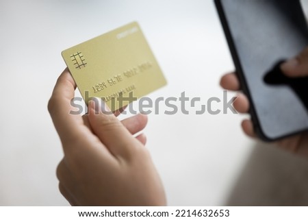 Close up unknown female hands holding modern smartphone and credit card, paying for goods or services, making instant money transfer remotely use mobile application, spend funds on-line, do e-shopping