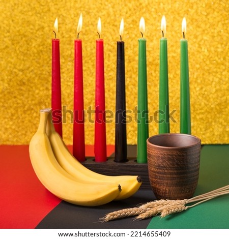 African Kwanzaa holiday concept with traditional lit candles, banana, bowl and ears of wheat 