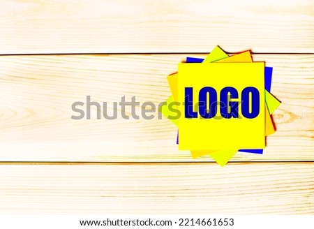 Multicolored office paper stickers with the text LOGO on a wooden background. copy space