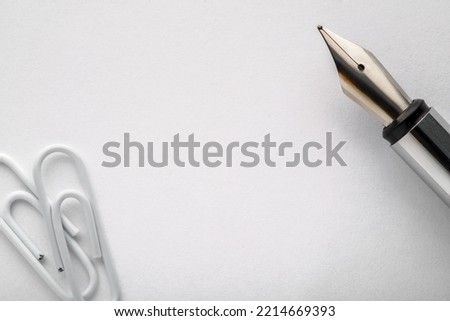 Fountain pen on a white paper with paper clips. Top view, copy space. Royalty-Free Stock Photo #2214669393