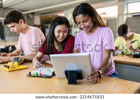 Group of diverse teenage students learning together to build electronic circuits at high school - Asian and african american female classmate working at technology class Royalty-Free Stock Photo #2214671831