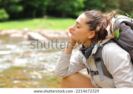 Profile of a hiker relaxing in a riverside with closed eyes Royalty-Free Stock Photo #2214672329