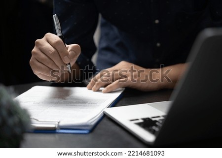 Hand holding pen writing paperwork business document financial investment or signature contract job and insurance on desk.
