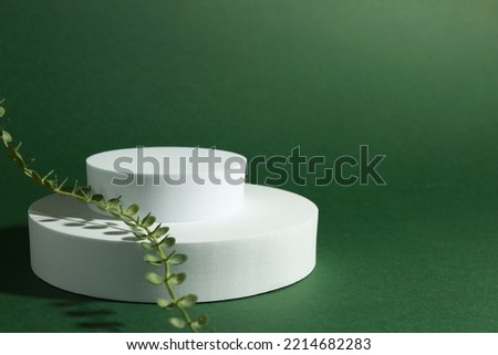 Product photography props. Round shaped podiums with plant on green background, space for text