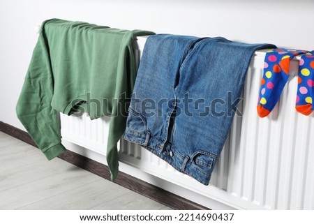 Clothes hanging on white radiator in room Royalty-Free Stock Photo #2214690437