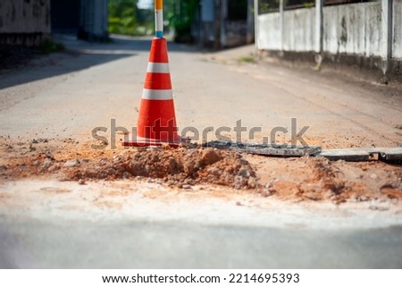traffic cone on damaged road surface, damaged road surfaces are being repaired