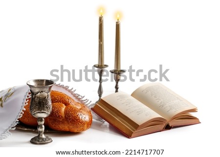 Challah bread covered with a special napkin, shabbat wine, torah and candles on white background. Traditional Jewish Shabbat ritual. Shabbat Shalom.