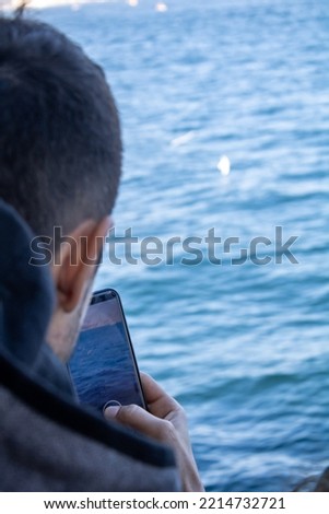 A person trying to take a photo with a phone is a person taking a sea photo. Selective Focus.