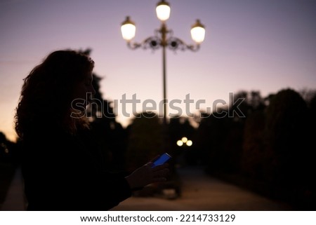 silhouette of woman using cell phone at night