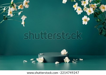 Podium, stand, showcase and delicate white flowers on dark teal background. Scene to show cosmetic products. Mock up. Trendy color 2023 Royalty-Free Stock Photo #2214749247