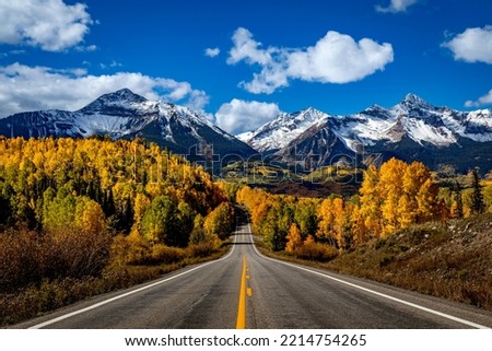 Stunning scenic fall drive along Colorado 145 near Telluride Colorado on a sunny afternoon with yellow Aspen trees near peak fall colors, and 2 lane highway in the foreground Royalty-Free Stock Photo #2214754265