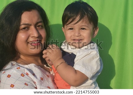 loving young Indian mother holding her  little son . green screen background. 