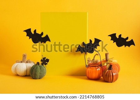 yellow plate mock-up and halloween decor on a bright yellow background, candles in a glass, homemade pumpkins, felt bats, space for text, advertising