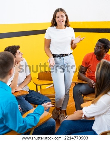 Confident girl talking to student group during brainstorming while preparing for exam together