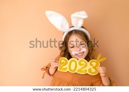 Funny girl shows golden numbers 2022 laughing merrily. Zodiac sign according to the Eastern calendar. Waiting for the new year of the rabbit