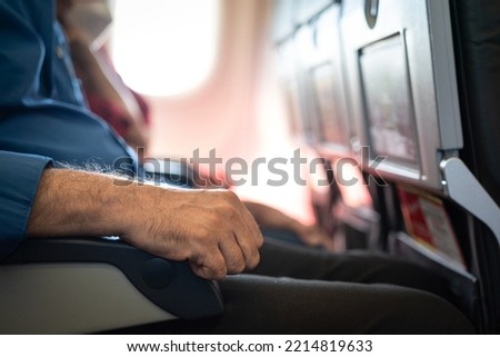 Hand of a airplane passenger is placed on an armrest during sitting at the economy class row. People in transportation action photo, selective focus. Royalty-Free Stock Photo #2214819633