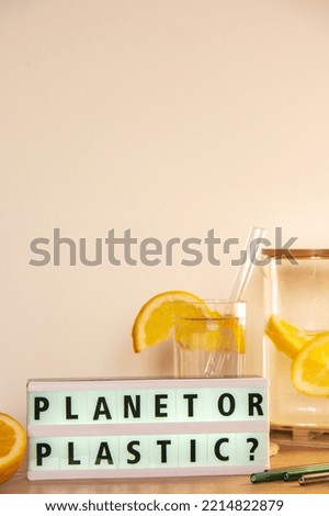 Lightbox with text PLASTIC OR PLANET Glass of water with fresh lemon juice with Reusable glass Straws Detox cold tonic water with sunny lemon slices Low-waste lifestyle Eco-Friendly Drinking Straw 