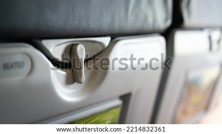 Close-up at part of table tray's securing pin on backrest of airplane passenger seat. Transportation vehicle equipment object, selective focus. Royalty-Free Stock Photo #2214832361