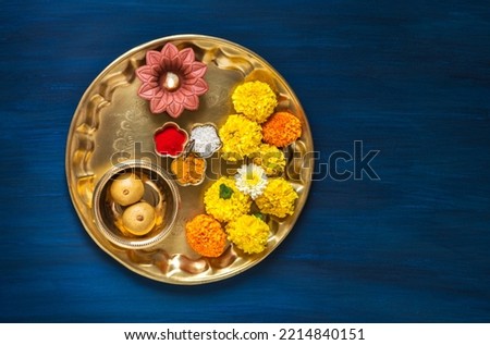 Top view of a Puja Thali for Hindu religious rituals. Flowers, diya, Prasad and kumkum in brass plate or Thali for Hindu auspicious occasions. Hindu religious objects. Royalty-Free Stock Photo #2214840151