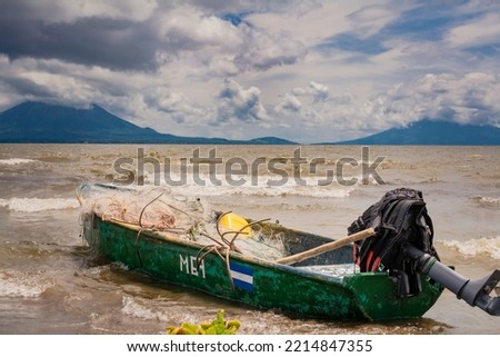A fishing boat on a lake in Nicaragua. Concept of fishing boats parked at the seaside, Fishing boat on the shore of a lake, A fishing boat on the shore of a lake with volcanoes in the background