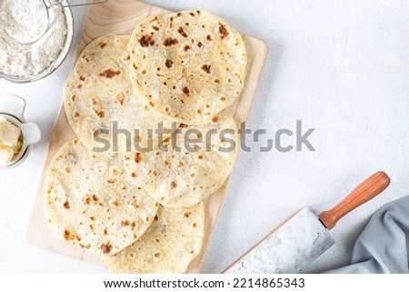 Homemade wheat tortillas, pita bread, tortilla, pita with ingredients for cooking on a white table. Top view. Copy space.