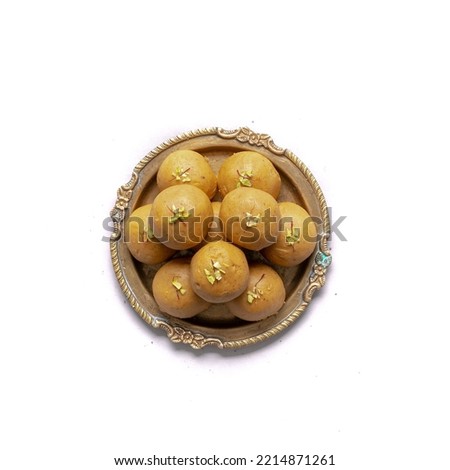 Besan ladoo or laddu in a gold plate are delicious sweet balls made with gram flour, sugar, ghee cardamoms, indian mithai made on diwali festival Royalty-Free Stock Photo #2214871261