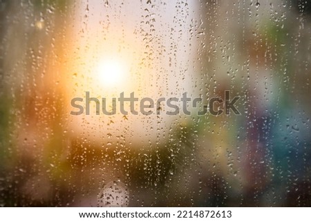 Rain drops on window glass for background rainy fall autumn weather with sun. Abstract backgrounds with raindrops on blurred daylight. Outside urban window is blurred bokeh water. Copy text space