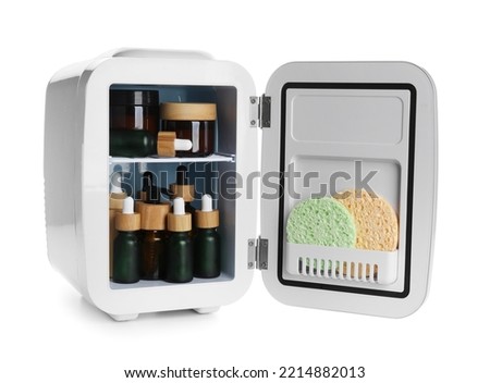 Small refrigerator with natural cosmetics and sponges on white background