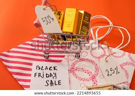 Beautiful packages with discounts lie near a shopping cart in which dollars and gold are isolated on a beautiful orange background. Black Friday concept. Discount concept
