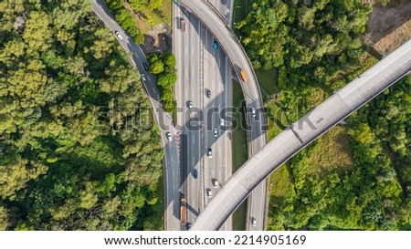 Aerial view directly above a six lane highway. Top view of asphalt road passes through the field and forest. Aerial. Sedan cars driving by the highway. Top view from drone. aerial photo autobahn road Royalty-Free Stock Photo #2214905169