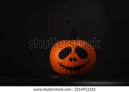 Halloween celebration. Pumpkin with drawn face on table in darkness, space for text