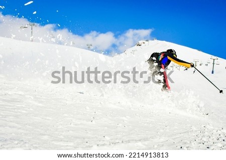 Dynamic picture of a skier on the piste in Alps. Woman skier in the soft snow. Active winter holidays, skiing downhill in sunny day.Ski rides on the track with swirls of fresh snow