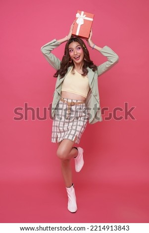 Happy beautiful Asian teen woman smile with red gift box isolated on pink background. Teenage girls in love, Receiving gifts from lovers. Christmas and Valentines Day concept.