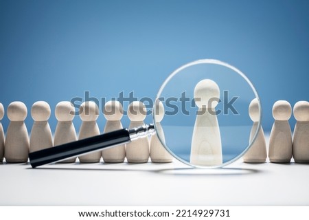Recruitment and job search magnifying glass with wooden people concept for human resources and choosing the right people